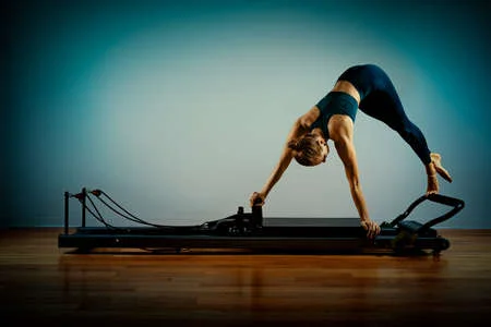 143950647 Young Girl Doing Pilates Exercises With A Reformer Bed Beautiful Slim Fitness Trainer On Reformer